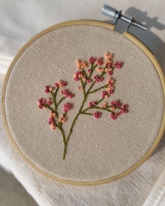 Bastidor con un ramito de flores rosas bordado a mano