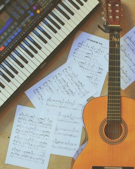 Una guitarra apoyada junto a partituras