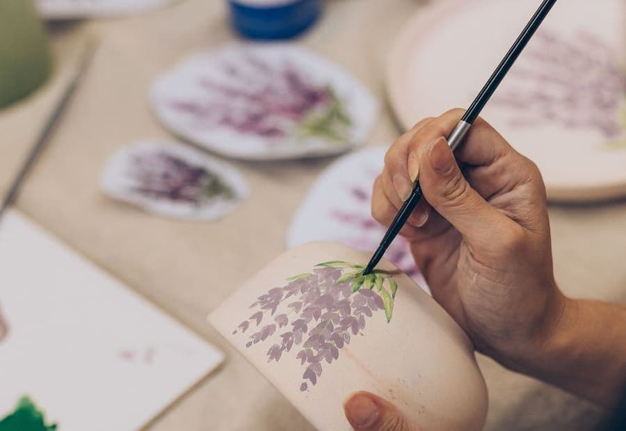 Manos pintando una taza de cerámica en un taller